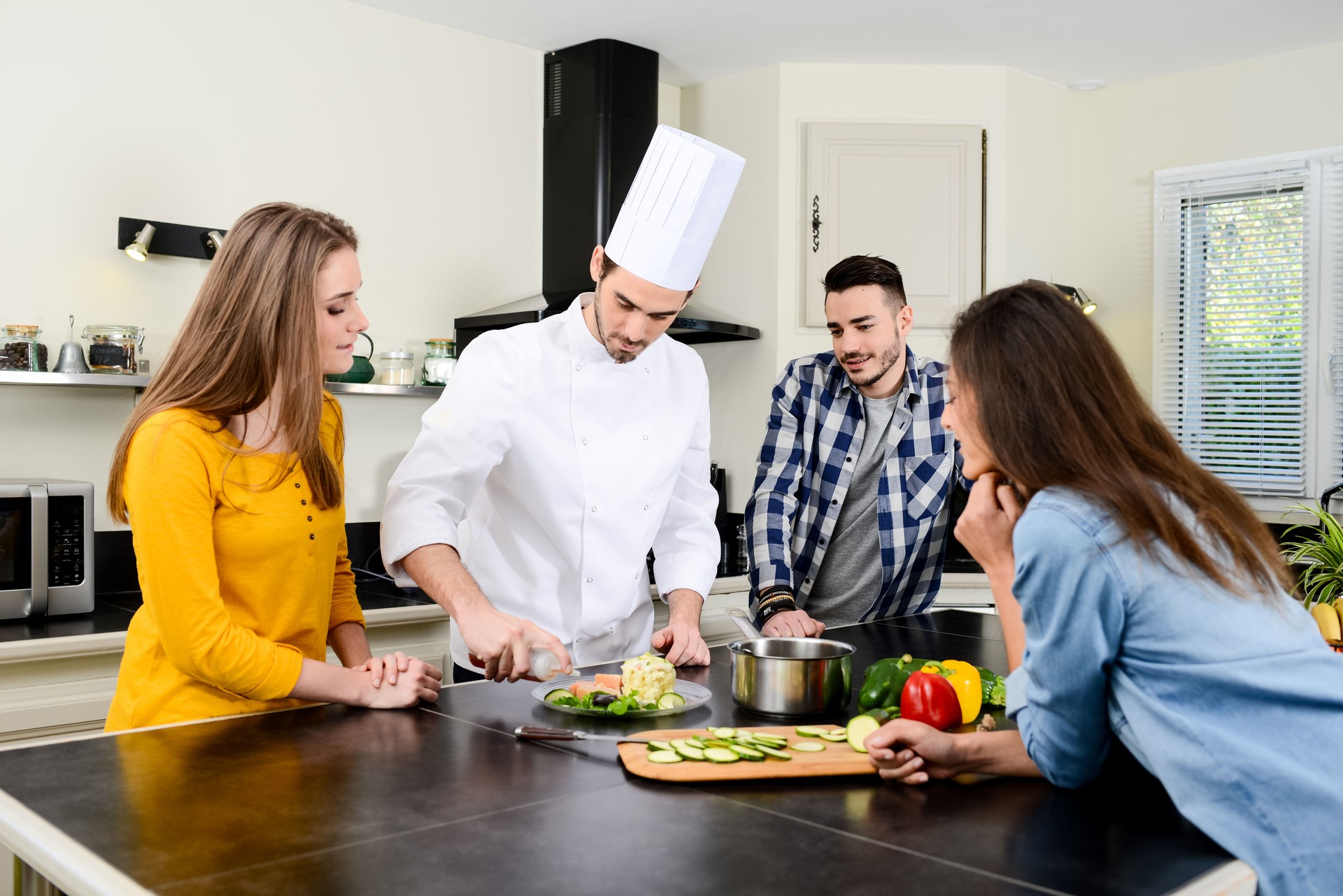 professional personal chef cook in customer's private kitchen house giving a cooking lesson to young people at home